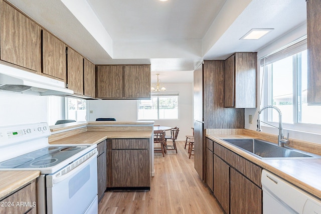 kitchen with white appliances, pendant lighting, light hardwood / wood-style flooring, sink, and a notable chandelier