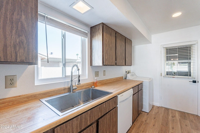 kitchen featuring light countertops, a sink, washer / dryer, light wood finished floors, and white dishwasher