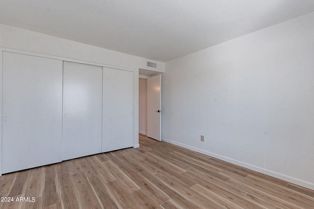 unfurnished bedroom featuring a closet, baseboards, visible vents, and light wood-type flooring