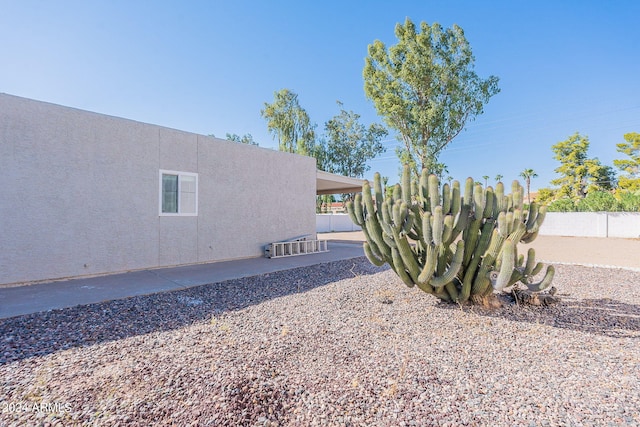 view of side of property with stucco siding and fence