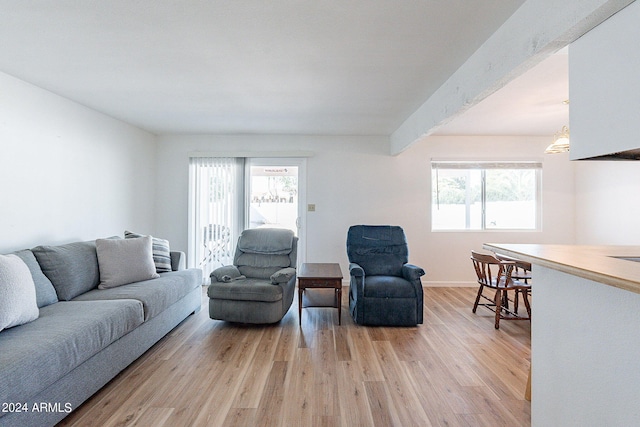 living room with beamed ceiling, plenty of natural light, and light hardwood / wood-style floors