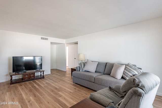 living room with baseboards, visible vents, and light wood-type flooring