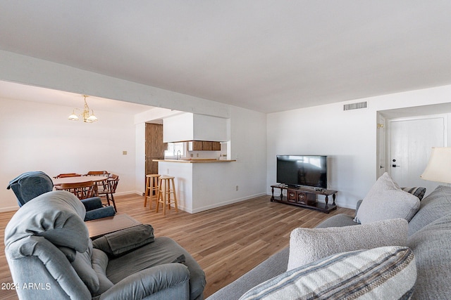 living area with baseboards, visible vents, light wood-style flooring, and an inviting chandelier