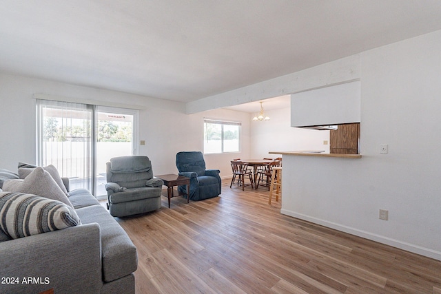 living room with wood-type flooring, an inviting chandelier, and a wealth of natural light