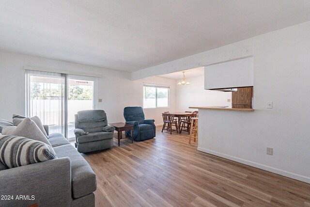 living room with an inviting chandelier, baseboards, and light wood-type flooring