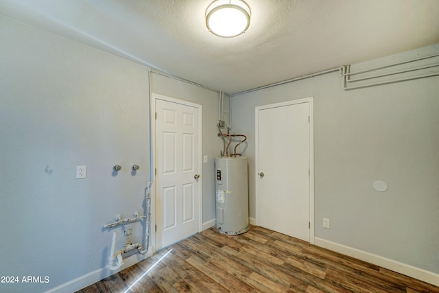 empty room featuring electric water heater, a textured ceiling, and wood-type flooring