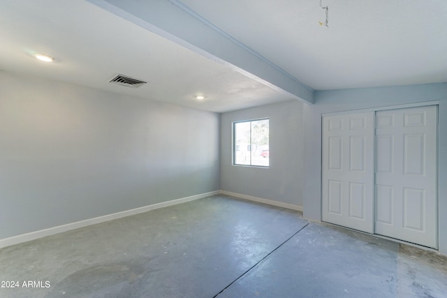 unfurnished bedroom featuring beam ceiling and a closet