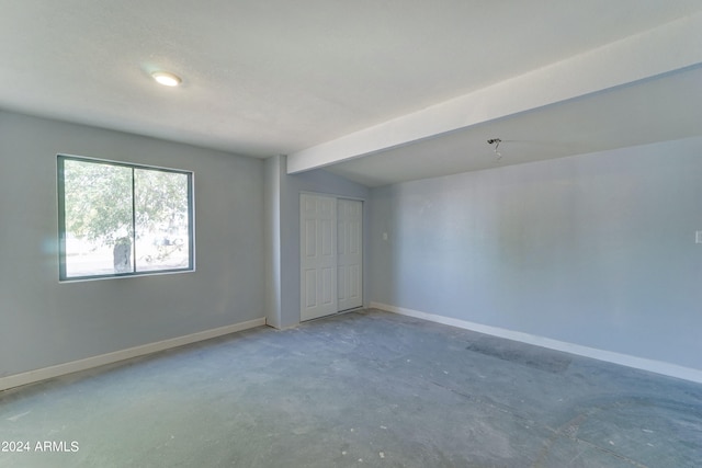 spare room with lofted ceiling with beams and concrete flooring