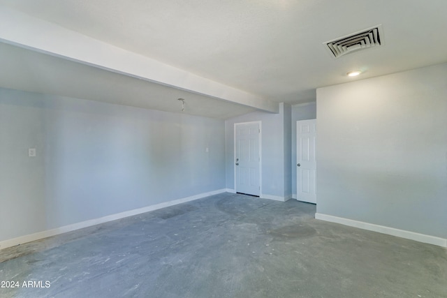 unfurnished room with concrete floors and beamed ceiling