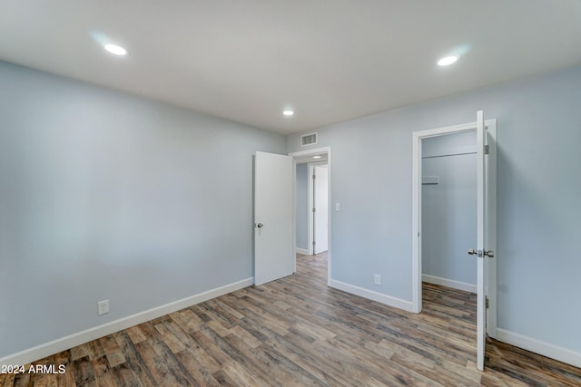 unfurnished bedroom with a walk in closet, hardwood / wood-style floors, and a closet