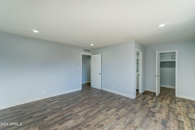 unfurnished bedroom with a spacious closet and dark wood-type flooring