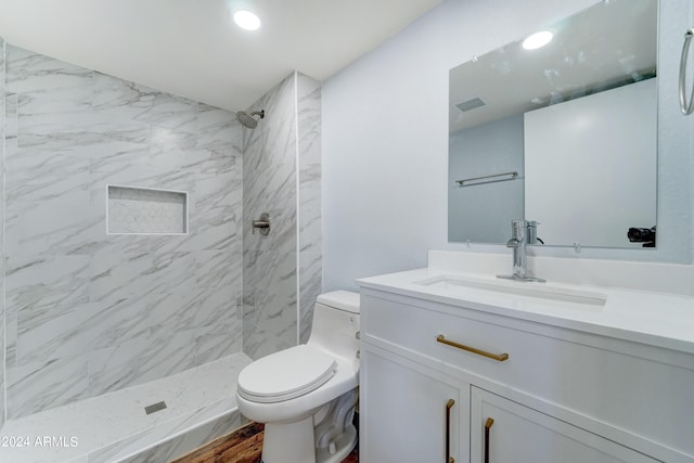 bathroom with vanity, toilet, a tile shower, and hardwood / wood-style floors