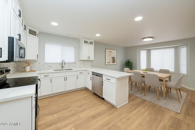 909 W San Mateo Ct, Gilbert, AZ 85233 - kitchen featuring appliances with stainless steel finishes, a sink, a peninsula, tasteful backsplash, and light wood-type flooring