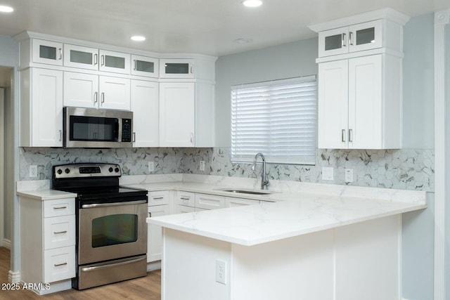 909 W San Mateo Ct, Gilbert, AZ 85233 - kitchen featuring stainless steel appliances, a sink, light wood finished floors, a peninsula, and white cabinets