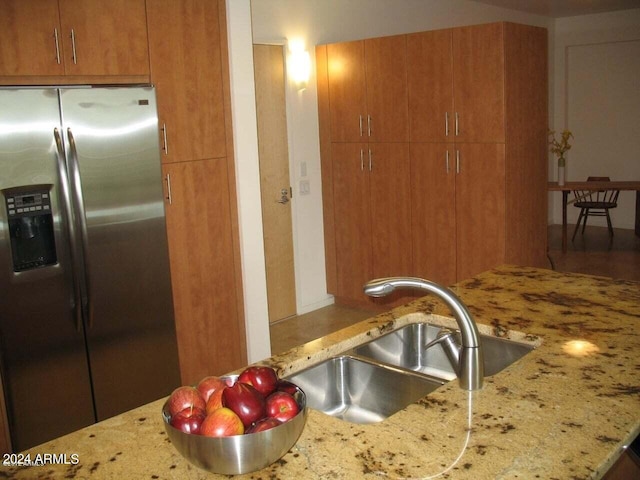 kitchen featuring sink, light stone countertops, and stainless steel fridge with ice dispenser