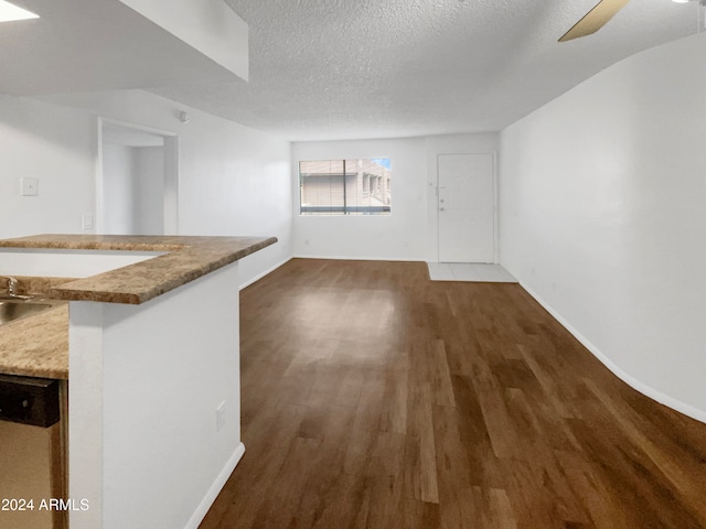 interior space with dark wood-type flooring, a textured ceiling, and ceiling fan