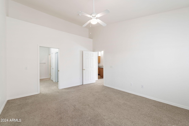 unfurnished bedroom with a walk in closet, ceiling fan, a towering ceiling, and light colored carpet