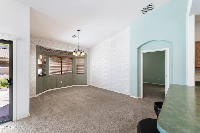 carpeted empty room featuring a notable chandelier