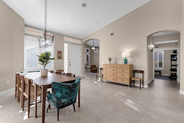 tiled dining area featuring high vaulted ceiling