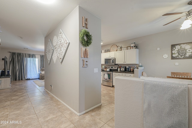 kitchen featuring stainless steel appliances, light tile patterned floors, ceiling fan, and white cabinets