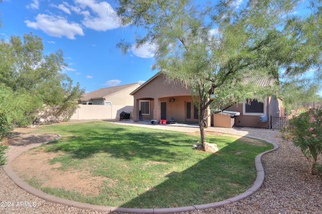 back of property featuring a jacuzzi, a lawn, and a patio