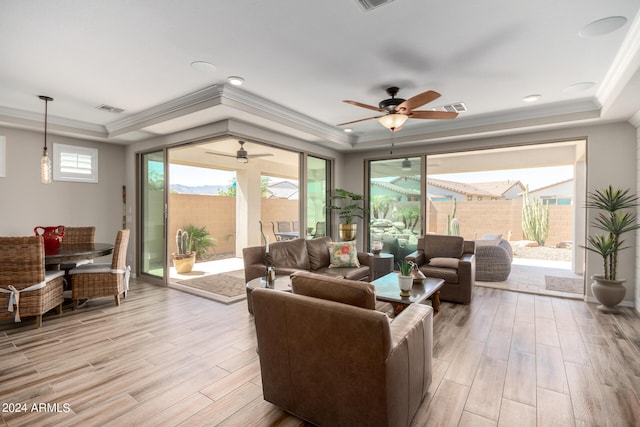 living room featuring ceiling fan, light wood-type flooring, and a raised ceiling