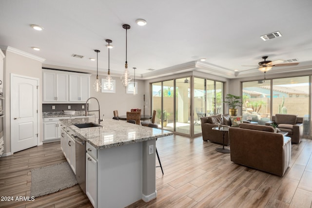 kitchen featuring an island with sink, white cabinetry, sink, and light hardwood / wood-style flooring