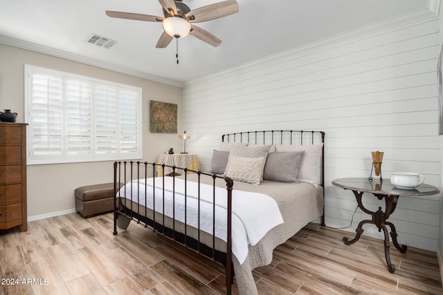 bedroom featuring wood walls, crown molding, light hardwood / wood-style flooring, and ceiling fan