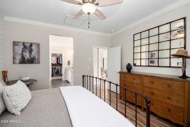 bedroom featuring light wood-type flooring, crown molding, a closet, and a spacious closet