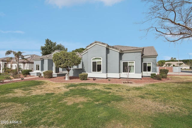 back of property featuring a tile roof, a yard, and stucco siding