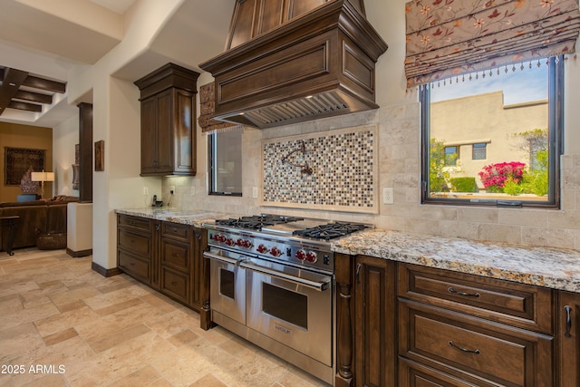 26156 N 88th Way, Scottsdale, AZ 85255 - kitchen with range with two ovens, custom range hood, backsplash, and dark brown cabinetry