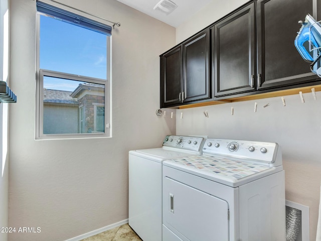 clothes washing area with cabinets, washing machine and dryer, and light tile patterned flooring