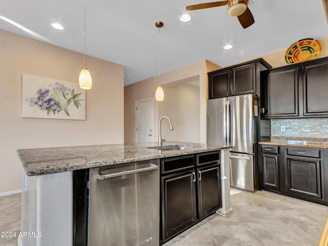 kitchen with pendant lighting, a center island with sink, sink, appliances with stainless steel finishes, and tasteful backsplash