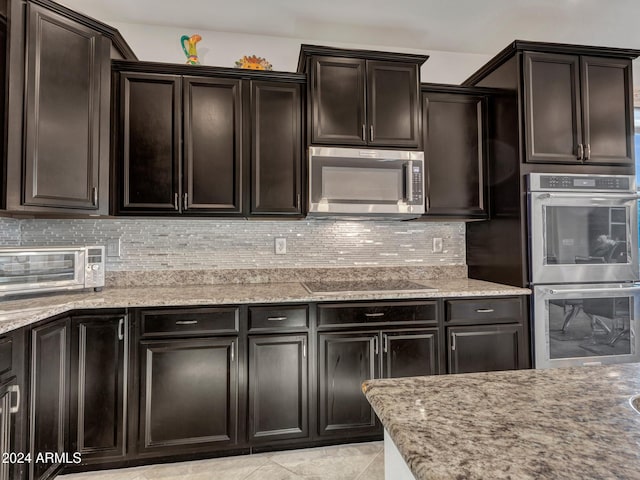 kitchen with decorative backsplash, light stone countertops, dark brown cabinetry, stainless steel appliances, and light tile patterned flooring