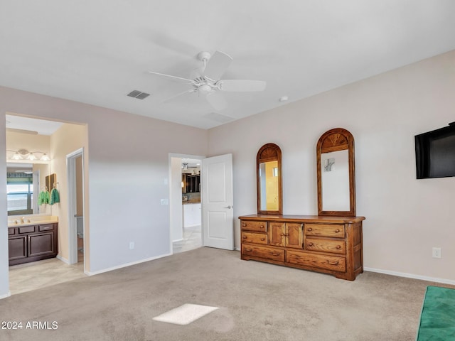 bedroom featuring ceiling fan, light colored carpet, and connected bathroom