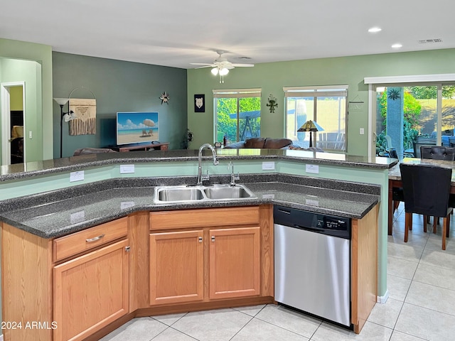 kitchen featuring ceiling fan, dishwasher, sink, dark stone countertops, and light tile patterned flooring