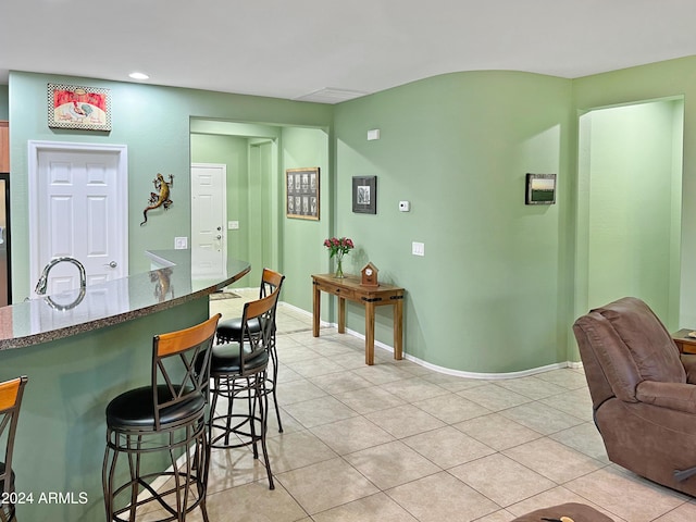 interior space with stainless steel fridge, a kitchen bar, light tile patterned floors, and sink