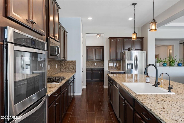 6788 S Jacqueline Way, Gilbert, AZ 85298 - kitchen with dark brown cabinets, appliances with stainless steel finishes, light stone counters, a sink, and backsplash