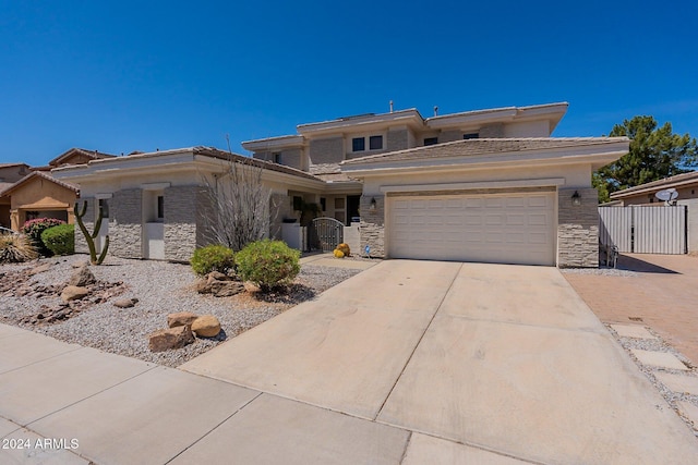 prairie-style house featuring a garage, stone siding, fence, and concrete driveway