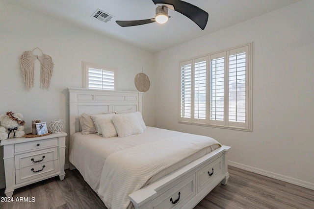 bedroom featuring dark wood-style floors, a ceiling fan, visible vents, and baseboards