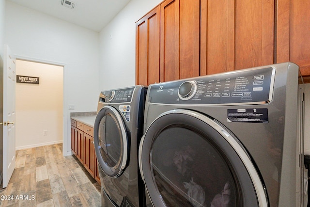 washroom with visible vents, separate washer and dryer, light wood finished floors, and cabinet space