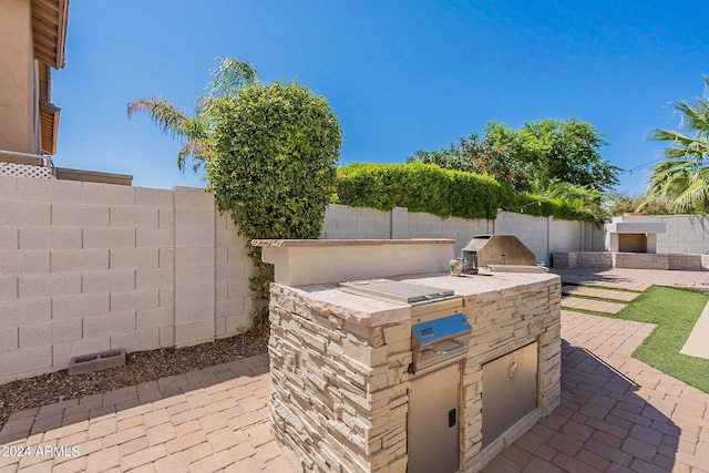 view of patio featuring a fenced backyard, an outdoor kitchen, and area for grilling