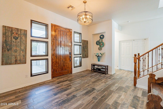 entryway with baseboards, visible vents, stairway, dark wood-style flooring, and a chandelier