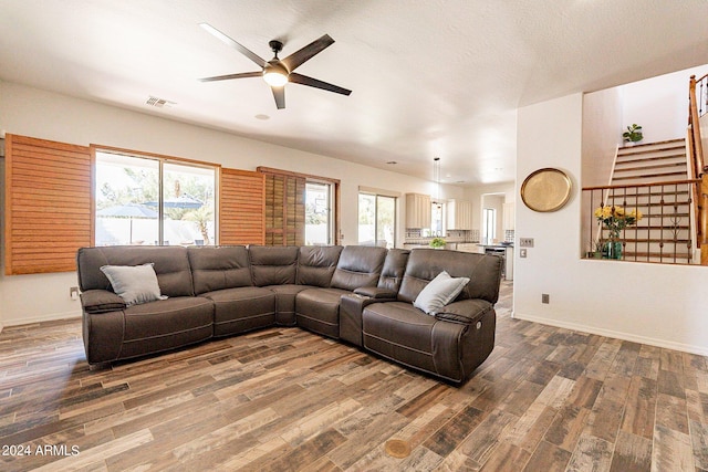 living area featuring visible vents, stairway, ceiling fan, wood finished floors, and baseboards