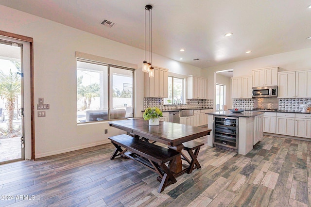 kitchen with wine cooler, decorative light fixtures, stainless steel appliances, dark countertops, and visible vents