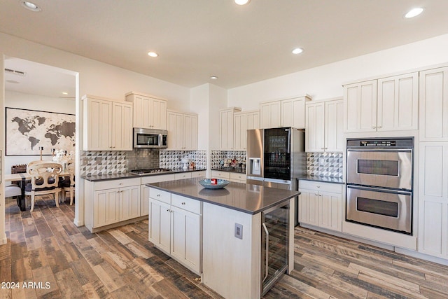 kitchen with beverage cooler, dark wood finished floors, dark countertops, a center island, and stainless steel appliances