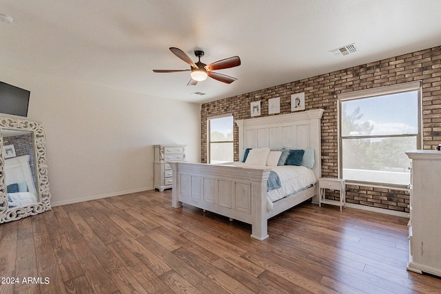 bedroom with brick wall, wood finished floors, and visible vents