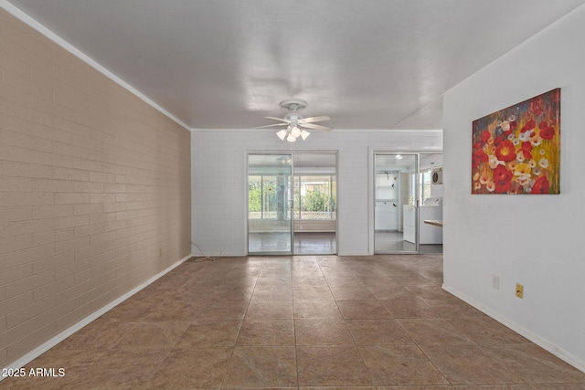 unfurnished room with brick wall, washer / clothes dryer, a ceiling fan, and tile patterned floors
