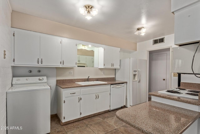 kitchen featuring white appliances, white cabinets, visible vents, a sink, and washer / dryer