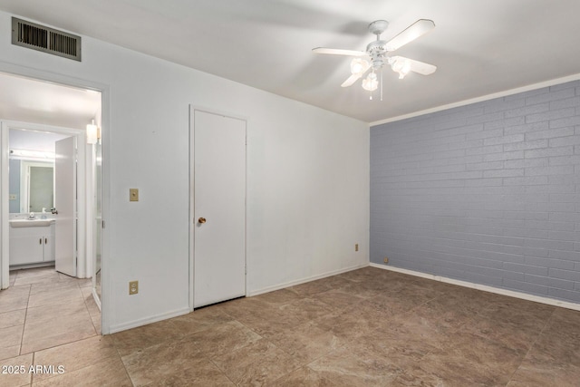 unfurnished bedroom with brick wall, baseboards, visible vents, and connected bathroom